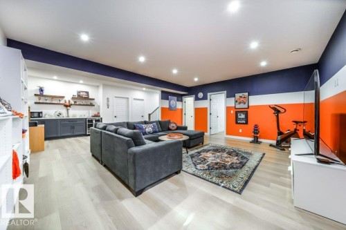 Spacious recreation room featuring light wood-finish flooring, recessed lighting, and a built-in wet bar with dark cabinetry and open shelving - 11303 111 Avenue, Edmonton, AB - Indoor