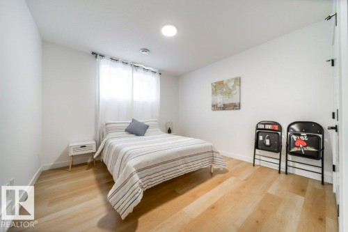 Light-filled room featuring wood-finish flooring, white walls, a recessed ceiling light, and a window with sheer white curtains - 11303 111 Avenue, Edmonton, AB - Indoor Photo Showing Bedroom