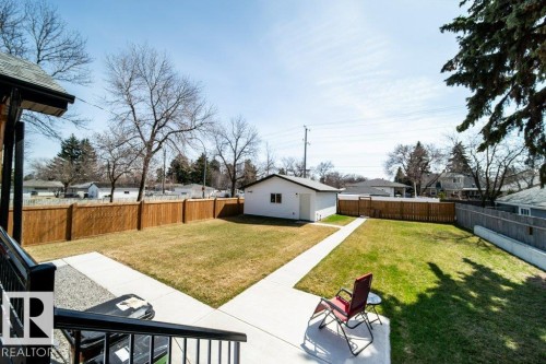 Expansive backyard featuring a manicured lawn, a detached white auxiliary building, and a privacy fence - 11303 111 Avenue, Edmonton, AB - Outdoor With Backyard