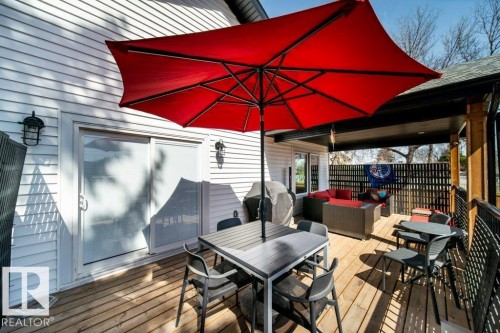 Spacious wood-finish deck with multiple seating areas, white horizontal siding, dark metal railing, and a black privacy screen - 11303 111 Avenue, Edmonton, AB - Outdoor With Deck Patio Veranda With Exterior