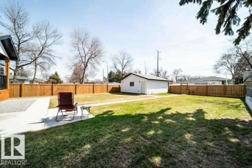 Spacious backyard featuring a manicured lawn, full perimeter wood fencing, and a concrete pathway - 11303 111 Avenue, Edmonton, AB - Outdoor With Backyard