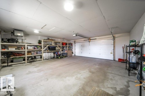 Spacious two-car garage featuring a concrete floor, built-in shelving, two overhead garage doors with automatic openers, and overhead lighting - 11303 111 Avenue, Edmonton, AB - Indoor Photo Showing Garage