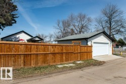 Detached garage with white siding, asphalt shingle roof, and concrete driveway - 
