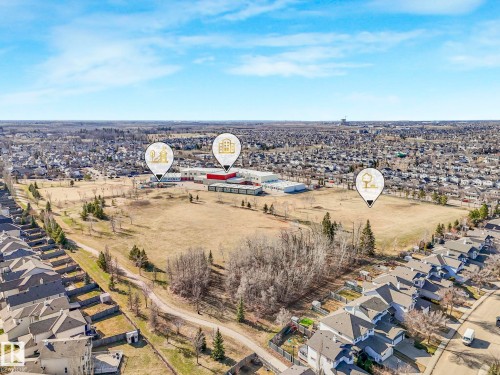 Aerial perspective showcasing suburban development with residential properties, a large open field, and institutional buildings - 322 1520 Hammond Gate Nw, Edmonton, AB - Outdoor With View