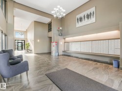Spacious entry lobby featuring high ceilings, large format tile flooring, contemporary chandelier, and built-in mailboxes with accent lighting - 