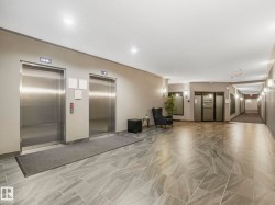 Elevator lobby featuring two stainless steel elevators, overhead recessed lighting, modern sconces, and large format tile flooring - 
