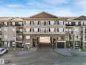 Multi-story building featuring a stone facade at the base, private balconies, and a central drive-through archway - 322 1520 Hammond Gate Nw, Edmonton, AB  - Outdoor With Balcony With Facade 