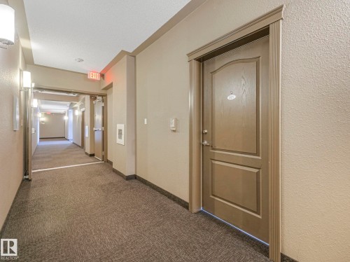 Contemporary hallway featuring textured neutral-toned walls, recessed lighting, and sconce fixtures - 322 1520 Hammond Gate Nw, Edmonton, AB - Indoor Photo Showing Other Room