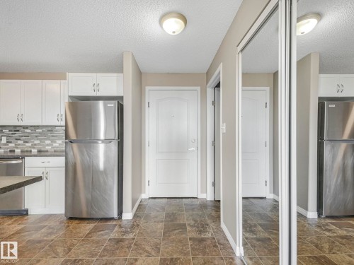 Kitchen with white cabinetry, stainless steel appliances, and a mosaic tile backsplash - 322 1520 Hammond Gate Nw, Edmonton, AB - Indoor Photo Showing Kitchen With Double Sink