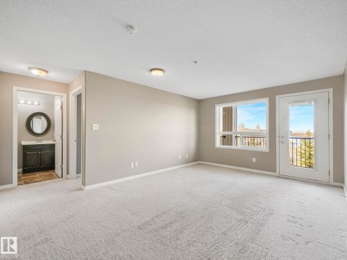 Carpeted living area with a white baseboard trim and neutral wall color - 322 1520 Hammond Gate Nw, Edmonton, AB - Indoor Photo Showing Other Room