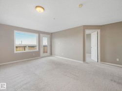 Carpeted living space featuring a window with a black railing, a door with glass panels, painted walls, and white trim - 