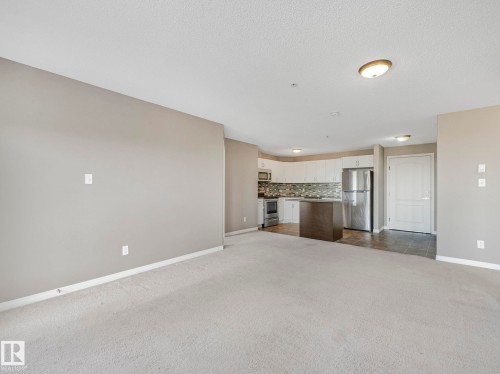 Open-concept living space featuring light gray carpeting and neutral wall paint - 322 1520 Hammond Gate Nw, Edmonton, AB - Indoor Photo Showing Other Room
