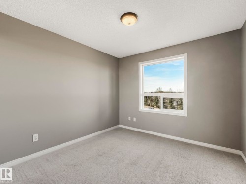 Room featuring neutral gray walls, light gray carpet flooring, white trim, and a white-framed window - 322 1520 Hammond Gate Nw, Edmonton, AB - Indoor Photo Showing Other Room
