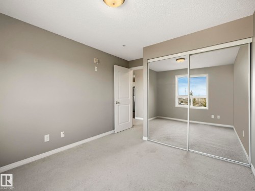 Bedroom featuring neutral wall paint, light-colored carpeting, white baseboards, and a white two-panel interior door - 322 1520 Hammond Gate Nw, Edmonton, AB - Indoor Photo Showing Other Room