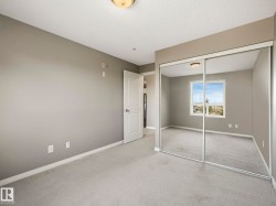 Bedroom featuring neutral wall paint, light-colored carpeting, white baseboards, and a white two-panel interior door - 