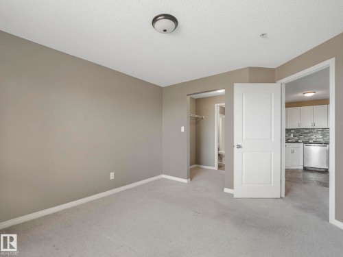 Carpeted room with neutral paint, featuring a ceiling-mounted light fixture - 322 1520 Hammond Gate Nw, Edmonton, AB - Indoor Photo Showing Other Room