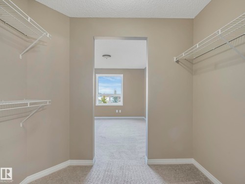Walk-in closet with neutral-toned walls, white wire shelving, and light-colored carpeting - 322 1520 Hammond Gate Nw, Edmonton, AB - Indoor With Storage