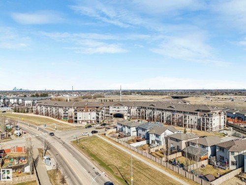 Aerial perspective showcasing a residential area with multi-story apartment buildings and single-family homes - 322 1520 Hammond Gate Nw, Edmonton, AB - Outdoor With View