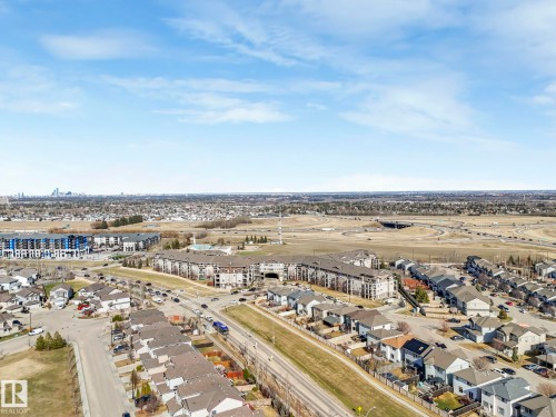 Aerial perspective showcasing a mixed-use neighborhood with residential properties and multi-story buildings - 322 1520 Hammond Gate Nw, Edmonton, AB - Outdoor With View