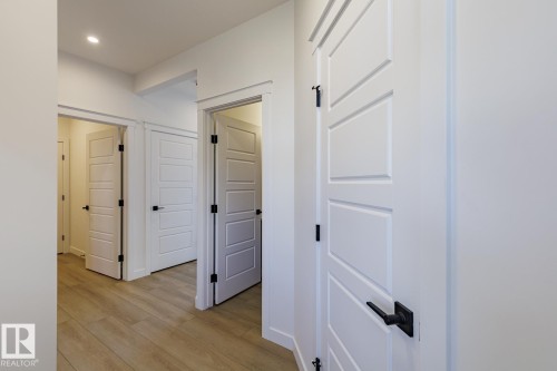 Hallway featuring wood-finish flooring, recessed lighting, white trim, and doors with matte black hardware - 6275 180 Avenue Nw, Edmonton, AB - Indoor Photo Showing Other Room