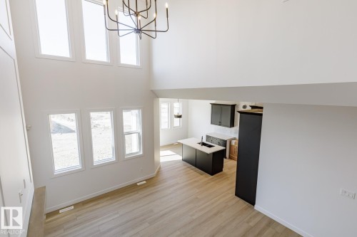 Open-concept living space with vaulted ceilings, a contemporary chandelier, and light wood-finish flooring - 6275 180 Avenue Nw, Edmonton, AB - Indoor Photo Showing Other Room