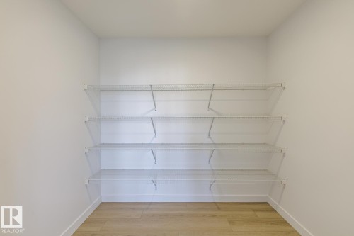 Walk-in closet featuring four tiers of wire shelving, white painted walls, and wood-finish flooring - 6275 180 Avenue Nw, Edmonton, AB - Indoor With Storage
