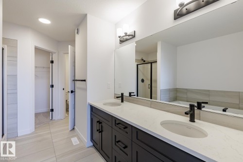Dual vanity with dark cabinetry, white countertops, and matte black fixtures - 6275 180 Avenue Nw, Edmonton, AB - Indoor Photo Showing Bathroom