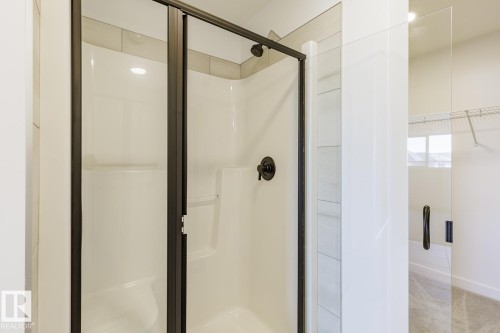 Walk-in shower featuring a dark-framed glass enclosure, integrated shelving, and matte black fixtures - 6275 180 Avenue Nw, Edmonton, AB - Indoor Photo Showing Bathroom