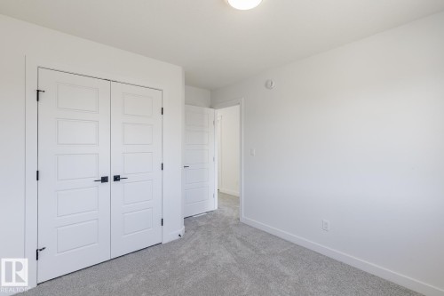 Dual white panel doors with matte black hardware, light gray carpeting, crisp white walls, and a recessed ceiling light fixture - 6275 180 Avenue Nw, Edmonton, AB - Indoor Photo Showing Other Room