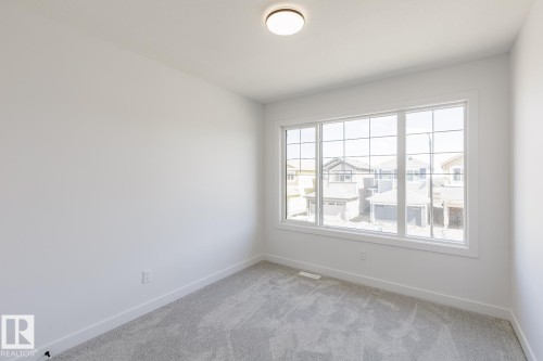 Room featuring light gray carpeting, crisp white walls, and a large multi-pane window - 6275 180 Avenue Nw, Edmonton, AB - Indoor Photo Showing Other Room