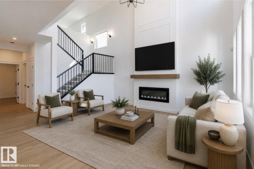 Living area featuring a two-story ceiling, light wood-finish flooring, and a modern fireplace with a wood mantle - 6275 180 Avenue Nw, Edmonton, AB - Indoor Photo Showing Other Room With Fireplace