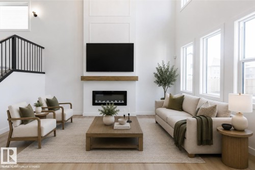 Living area featuring high ceilings and light wood-finish flooring - 6275 180 Avenue Nw, Edmonton, AB - Indoor Photo Showing Living Room With Fireplace