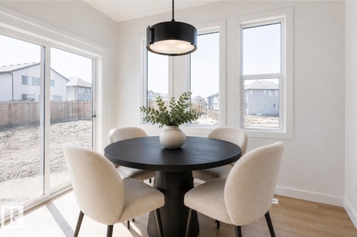 Bright dining area featuring a modern black chandelier, wood-finish flooring, and white walls - 6275 180 Avenue Nw, Edmonton, AB - Indoor Photo Showing Dining Room