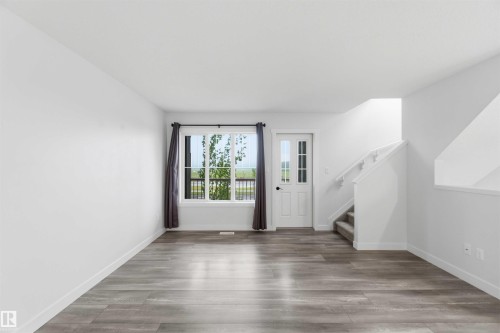 Spacious interior featuring wide plank wood-finish flooring and a bright window with exterior views - 36 1005 Graydon Hill Boulevard, Edmonton, AB 