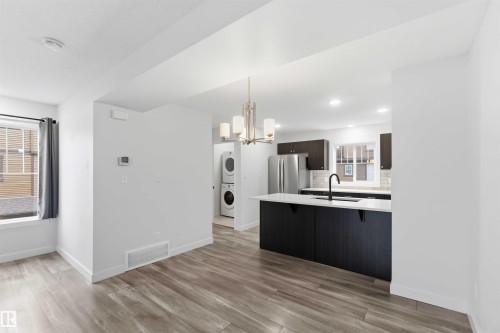 Modern kitchen with a central island, dark cabinetry, and integrated stainless steel appliances - 36 1005 Graydon Hill Boulevard, Edmonton, AB 