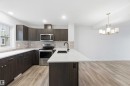 Modern kitchen featuring dark wood-finish cabinetry, light stone-look countertops, and a subway tile backsplash - 36 1005 Graydon Hill Boulevard, Edmonton, AB 