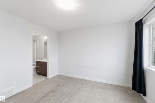 Spacious room with light neutral carpeting, white walls, and a large window providing natural light - 36 1005 Graydon Hill Boulevard, Edmonton, AB 