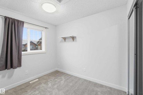 Bright room featuring a window with white trim, gray carpet, white walls, and a flush mount ceiling light - 36 1005 Graydon Hill Boulevard, Edmonton, AB 