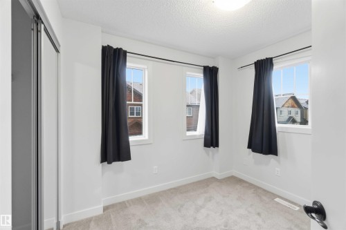 Neutral-toned room with light gray carpet, white walls, and bright overhead lighting - 36 1005 Graydon Hill Boulevard, Edmonton, AB 