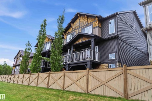 Contemporary multi-story exterior with horizontal dark siding, natural wood shingles, and an upper-level balcony with metal railings - 36 1005 Graydon Hill Boulevard, Edmonton, AB 