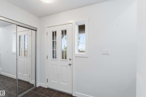 Entryway featuring a white paneled door with glass inserts, an adjacent vertical window, and dark tiled flooring - 36 1005 Graydon Hill Boulevard, Edmonton, AB 