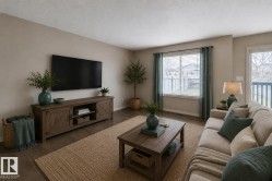 Spacious living area featuring wood-finish flooring, a neutral color palette, and a large window with horizontal blinds - 