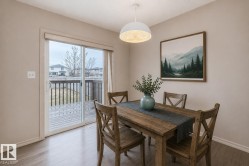 Dining area featuring wood-finish flooring, a contemporary pendant light fixture, and direct access to an outdoor deck via sliding glass doors - 