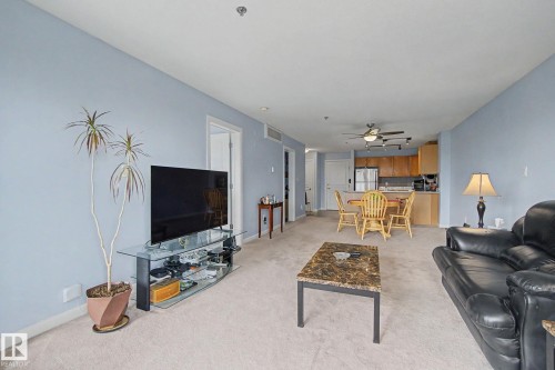 Open-concept living area featuring light blue walls and neutral carpet flooring - 303 530 Hooke Road, Edmonton, AB - Indoor Photo Showing Living Room