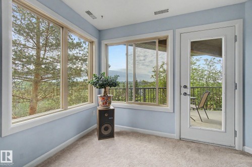 Room featuring expansive windows providing abundant natural light, light blue wall paint, and neutral carpeting - 303 530 Hooke Road, Edmonton, AB - Indoor Photo Showing Other Room