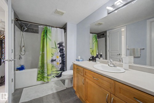 Bathroom featuring a single vanity with a laminate countertop, undermount sink, and wood-finish cabinetry - 303 530 Hooke Road, Edmonton, AB - Indoor Photo Showing Bathroom