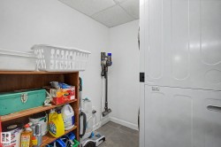 Dedicated laundry area featuring a white stackable washer and dryer, white walls, and gray tile flooring - 