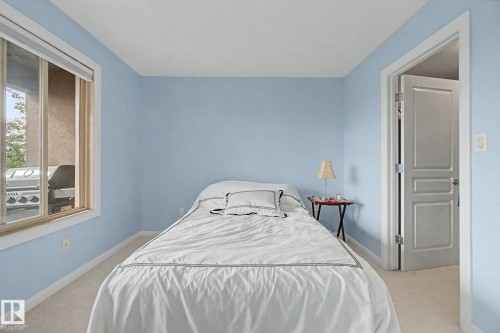 Carpeted bedroom featuring light blue walls, white trim, and a window with blinds - 303 530 Hooke Road, Edmonton, AB - Indoor Photo Showing Bedroom