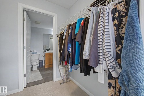 Carpeted area with a wire shelving system and an open doorway revealing a bathroom - 303 530 Hooke Road, Edmonton, AB - Indoor With Storage