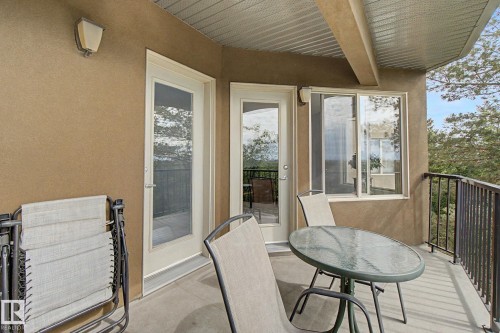 Private balcony with textured exterior finish, featuring two glass-paned doors, a sliding window, and a dark metal railing - 303 530 Hooke Road, Edmonton, AB - Outdoor With Deck Patio Veranda With Exterior